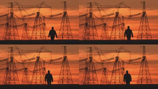 在一个能源变电所检查期间，在红色日落沿着电力线的主管剪影的广泛镜头。高清在线视频素材下载