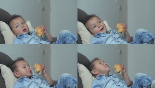一个男孩在家里的客厅里吃面包高清在线视频素材下载