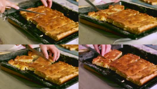 一个女人用带边的烤盘上的刀切刚烤好的、热气腾腾的奶酪土豆馅饼。高清在线视频素材下载