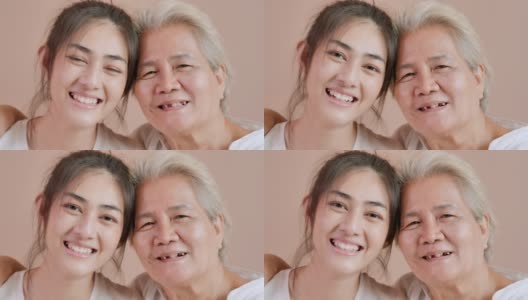 特写，肖像快乐的志愿者亚洲年轻女性护士照顾与亚洲老年母亲病人期间看在家里的相机。家庭工作室高清在线视频素材下载
