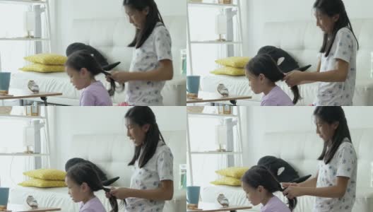 手亚洲女孩在家里编她的姐姐的头发，孩子一起玩，生活理念。高清在线视频素材下载