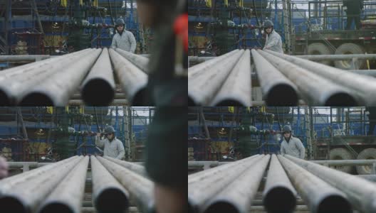 一个20多岁的年轻油田工人在一个寒冷的早晨在石油和天然气钻井平台上测量钻杆的慢动作镜头高清在线视频素材下载