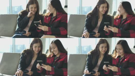 两名亚洲女性在机场出发区使用智能手机高清在线视频素材下载