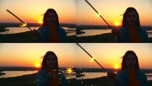 夕阳西下时，一名年轻女子手持荧光棒站在小山上高清在线视频素材下载