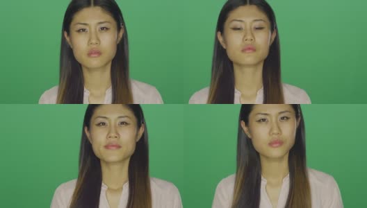 美丽的亚洲女人凝视前方，然后微笑，在一个绿色屏幕的工作室背景高清在线视频素材下载