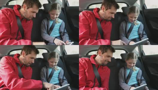 微笑的父亲和女儿用平板电脑坐在车内4K 4K高清在线视频素材下载