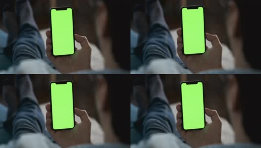 一个男人的手拿着一个绿色屏幕的智能手机看和显示一个新的应用程序，在线工作的特写高清在线视频素材下载
