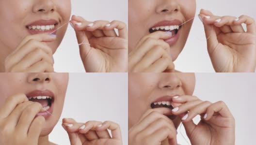 口腔卫生的概念。近距离拍摄的女人清洁她的健康牙齿与牙线，白色的背景，自由的空间高清在线视频素材下载