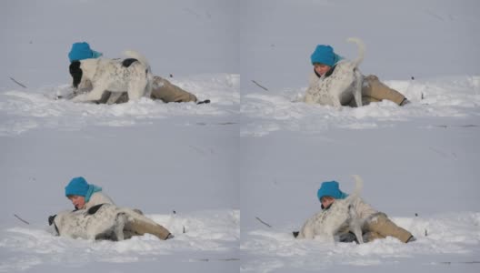 男孩十几岁在冬天的雪地里逗着狗玩。高清在线视频素材下载
