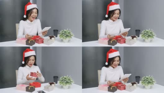 戴着圣诞帽的快乐女人在网上用电子平板电脑购买圣诞礼物高清在线视频素材下载