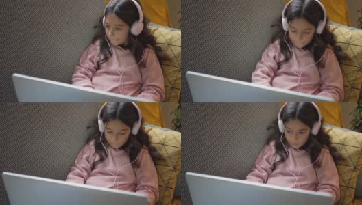 一名女小学生躺在沙发上用笔记本电脑做作业高清在线视频素材下载