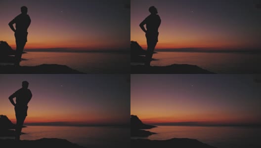 一个人的剪影看着月亮和星星在海洋的地平线上。高清在线视频素材下载