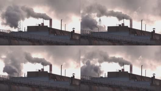 巨大的烟雾和蒸汽从工厂的烟囱里冒出来，背景是傍晚的天空，工业。制造业高清在线视频素材下载