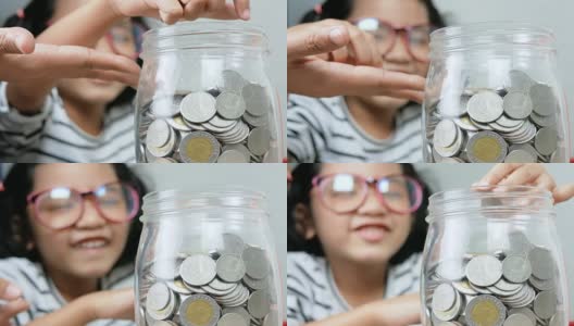 亚洲小女孩将硬币放入一个浅景深的玻璃罐中，选择焦点放在罐中高清在线视频素材下载