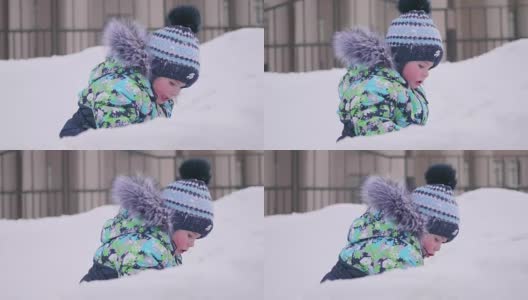 一个小孩在雪山上玩，扔雪，笑。阳光明媚的一天。新鲜的空气里充满了乐趣和游戏。高清在线视频素材下载