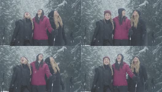 在一个下雪天，三位年轻的女士试图用她们的舌头捕捉雪，并对着镜头微笑高清在线视频素材下载