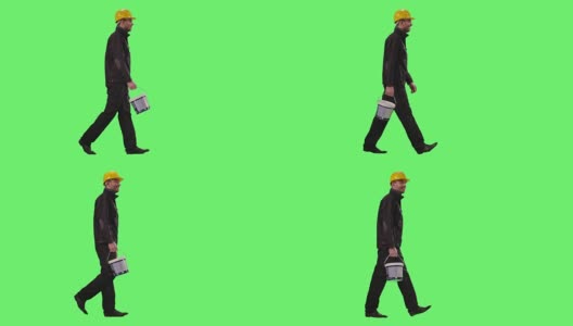 建筑工人戴着安全帽，背着油漆桶在绿色屏幕上行走。高清在线视频素材下载