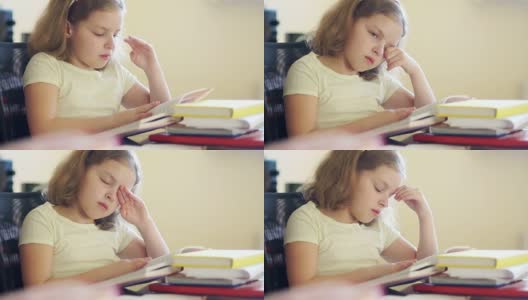悲伤的女孩坐在一堆书的桌子旁。她揉了揉眼睛，想睡觉。学校教育的问题。回到学校高清在线视频素材下载