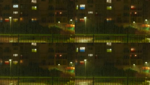 外面下雨时，水珠落在窗户上。散焦多层建筑与窗户照明和活动的背景。延时4k视频。高清在线视频素材下载