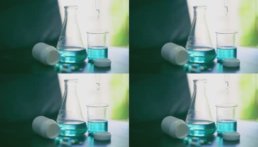 明亮的慢动作化学溶液滴在烧杯上，用于测试桌上药物的化学反应高清在线视频素材下载