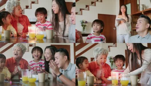 中国多代同堂的家庭在室内庆祝生日，一个小孩吹蜡烛在蛋糕上高清在线视频素材下载