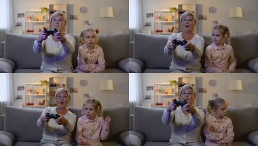 兴奋的老奶奶玩电子游戏，不顾伤心的孙子坐在沙发上上瘾高清在线视频素材下载