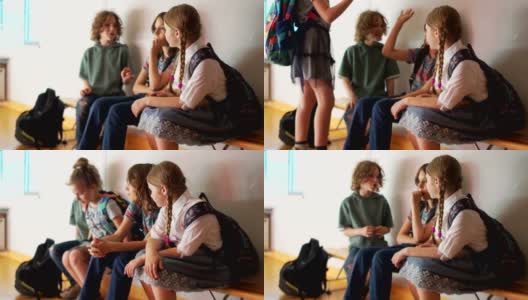 课间休息时，同学们坐在走廊的长凳上聊天。一个十几岁的女孩向她的朋友打招呼高清在线视频素材下载