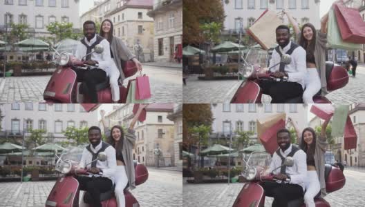可爱的快乐的混合种族夫妇坐在摩托车和女孩在她的手中购买的背景城市建筑高清在线视频素材下载