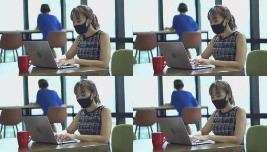 亚洲女员工戴口罩，在商务办公室使用笔记本电脑，与同事保持社交距离，以保护冠状病毒或covid-19疫情大流行。职场新常态政策高清在线视频素材下载