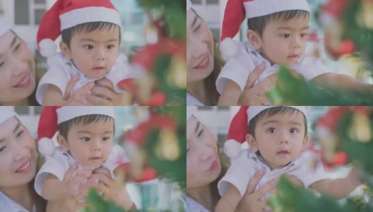 可爱的小男孩和妈妈看着圣诞树，寻找礼物。高清在线视频素材下载
