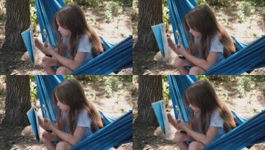 小女孩坐在吊床上看着夏令营里的地图。童军正在森林里进行定向运动。儿童概念地图阅读技巧高清在线视频素材下载
