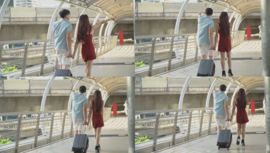 背影背影的年轻亚洲夫妇旅行者与行李在步行和观光在城市交谈。情人旅游者在假期外出旅游。高清在线视频素材下载
