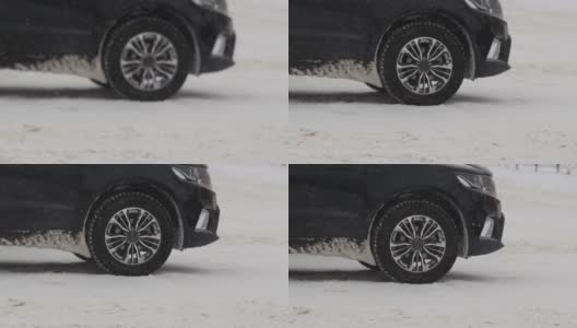 汽车正站在冬天城市里白雪覆盖的十字路口。降雪。车轮的慢动作特写。轮胎面。交通状况不佳，暴风雪。危险之旅高清在线视频素材下载