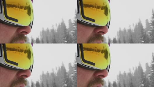 滑雪者滑下滑雪道的慢动作镜头在一个男性滑雪板的护目镜的反射在一个阴天的冬天在滑雪斜坡高清在线视频素材下载