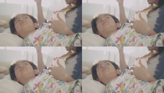 一个亚洲小男孩躺在医院的病床上。高清在线视频素材下载