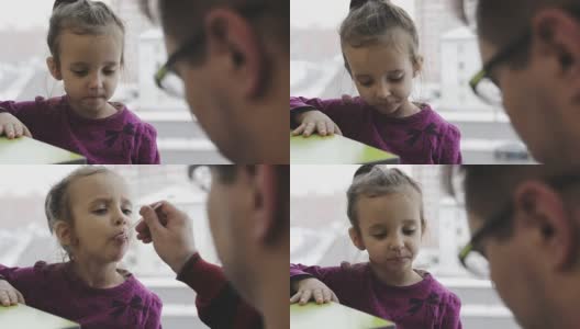 在咖啡馆里，一位年轻的父亲用勺子喂小孩。高清在线视频素材下载