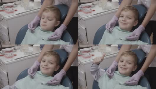 一个微笑的小男孩在牙医椅上竖起大拇指高清在线视频素材下载