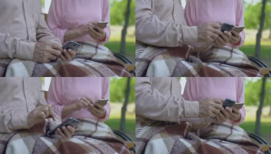一对老夫老妻在玩手机，坐在公园长椅上，用现代科技高清在线视频素材下载