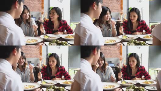 四名亚洲年轻人，一男三女，在咖啡馆和餐馆边吃边聊。友谊的概念高清在线视频素材下载