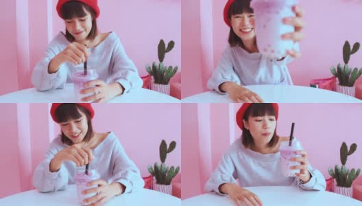 年轻的亚洲千禧一代女性在粉色柔和的咖啡馆喝冰珍珠奶茶高清在线视频素材下载