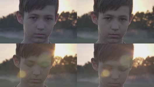 一个悲伤的男孩在麦田里的肖像在日落看近镜头高清在线视频素材下载