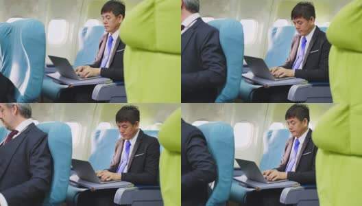 亚洲商人坐在商务舱在飞机上用笔记本电脑工作。男人很忙，眼睛感到很累。医疗保健关注和技术为商业人士的理念。高清在线视频素材下载