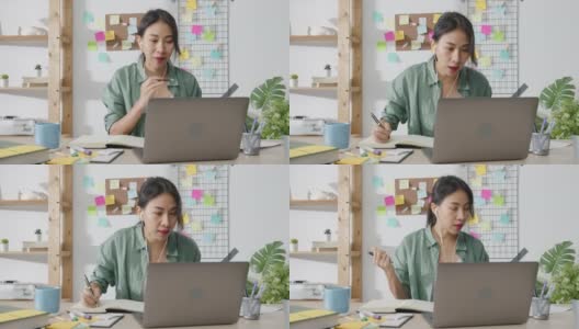 亚洲商业女性使用笔记本电脑与同事在视频通话中讨论计划，而智能工作在家客厅。高清在线视频素材下载