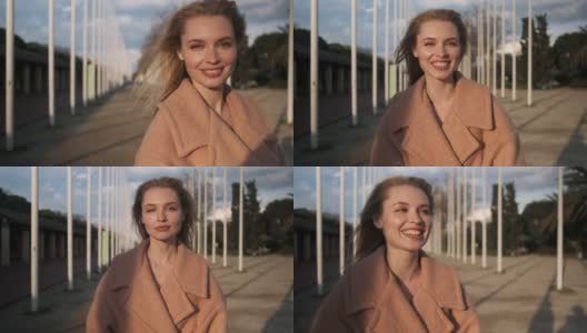 漂亮的金发女孩的肖像微笑和幸福地看着在街上的相机在日落高清在线视频素材下载