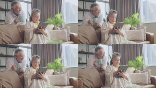 亚洲老年退休夫妇在沙发上与家人一起享受视频通话，幸福地笑着笑着，快乐地呆在家里，亚洲老年成熟成人居家隔离期概念高清在线视频素材下载