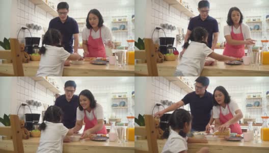 一对亚洲夫妇带着可爱的小女儿一起在厨房准备早餐高清在线视频素材下载