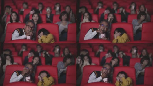 亚洲华人活跃的老人和他的孙女在电影院看恐怖惊悚电影高清在线视频素材下载