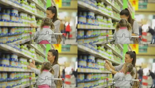 快乐家庭在店内选购产品的侧视图。微笑的女人站在货架旁边的货物，小女孩坐在购物车里高清在线视频素材下载