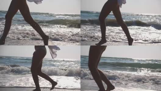 女性的脚在潮湿的沙子和海浪在海滩的海水上奔跑的特写。年轻女子在岸边奔跑的双腿。光着脚的女孩在海边。暑假或假日概念。慢动作侧视图低角度视图高清在线视频素材下载