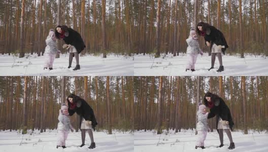 一名年轻女子和她的女儿站在冬天的森林里，向镜头挥手高清在线视频素材下载
